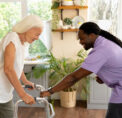 Occupational therapist assisting an elderly woman using a walker in a bright home environment, demonstrating safe mobility support for aging in place