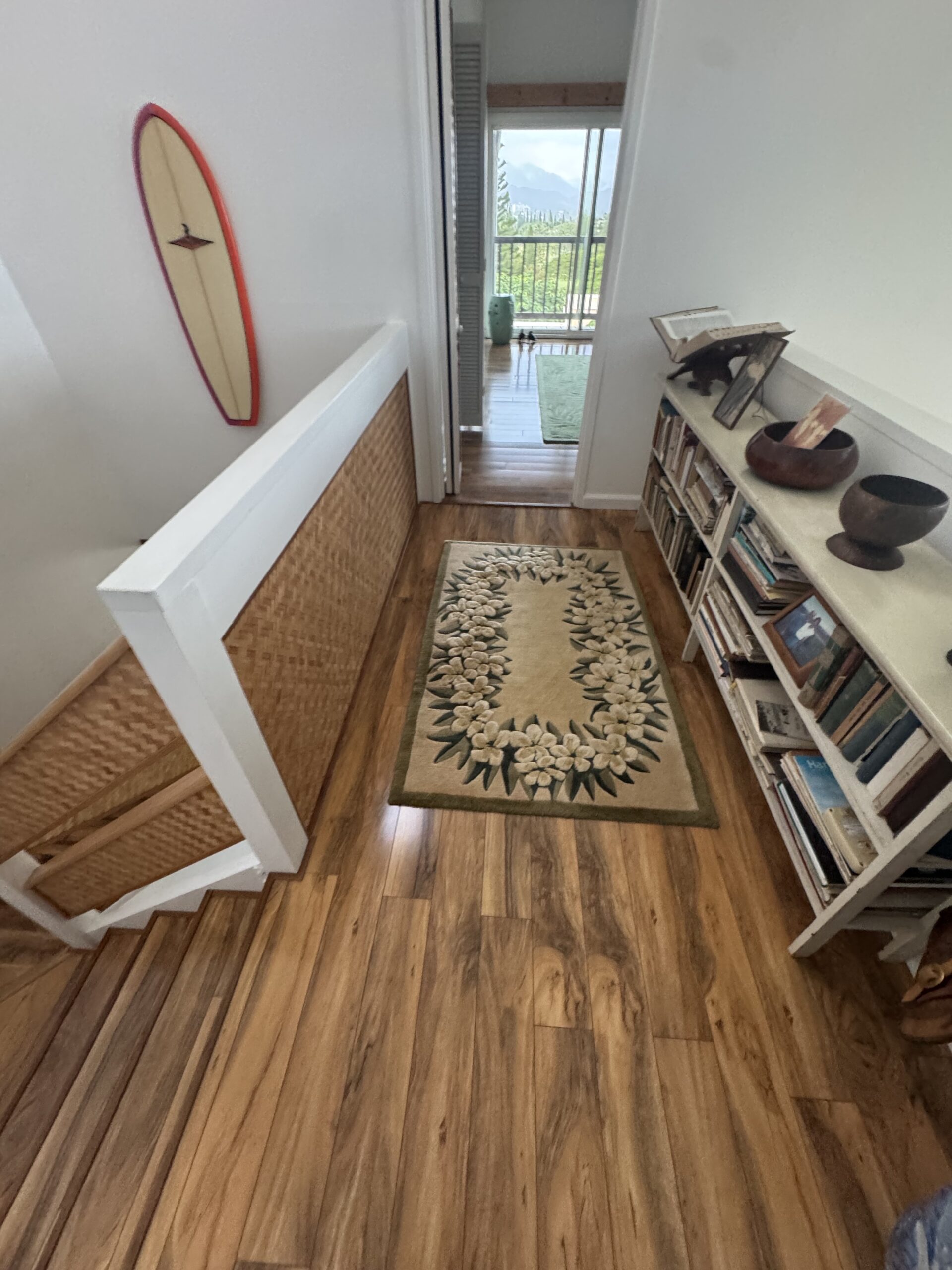 Before: upper landing beside woven stair panels, a rug and bookcase.
