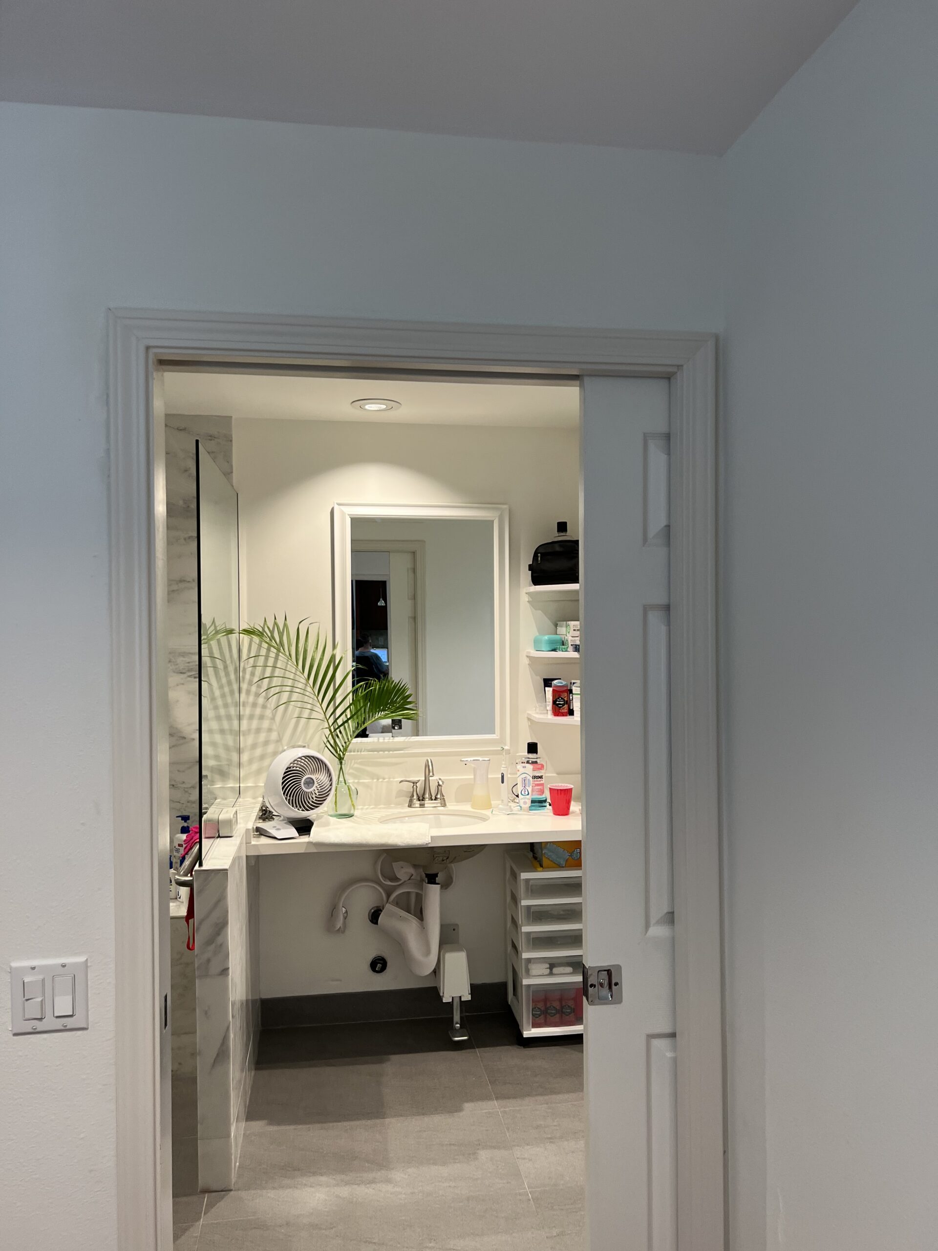 Before: bathroom doorway, wall switches and vanity without an overhead lift track.