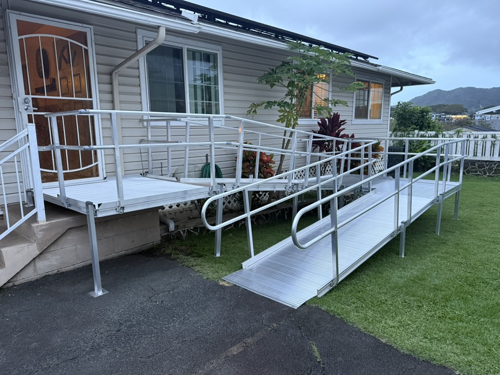 After: aluminum ramp, turning platform and handrails leading to the same front door beside the window and garden bed.