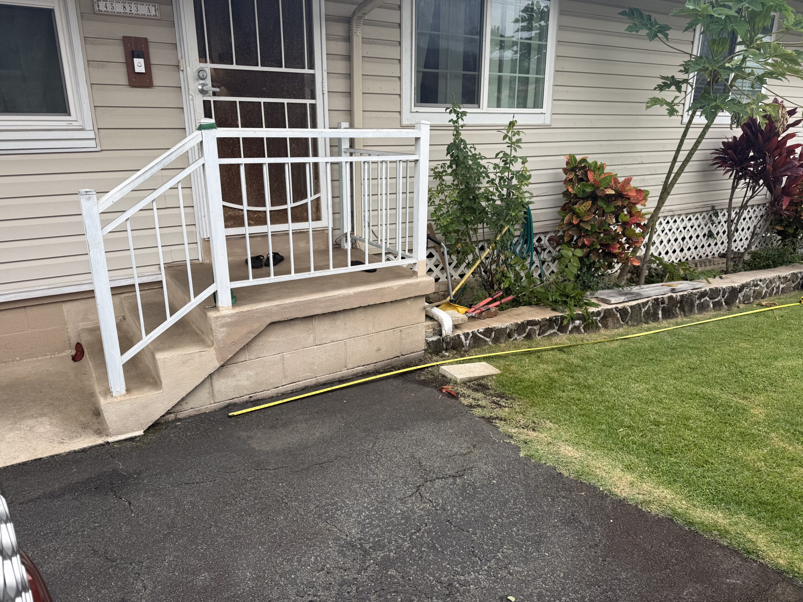 Before: concrete entrance steps with white handrails beside a front door, window and garden bed.