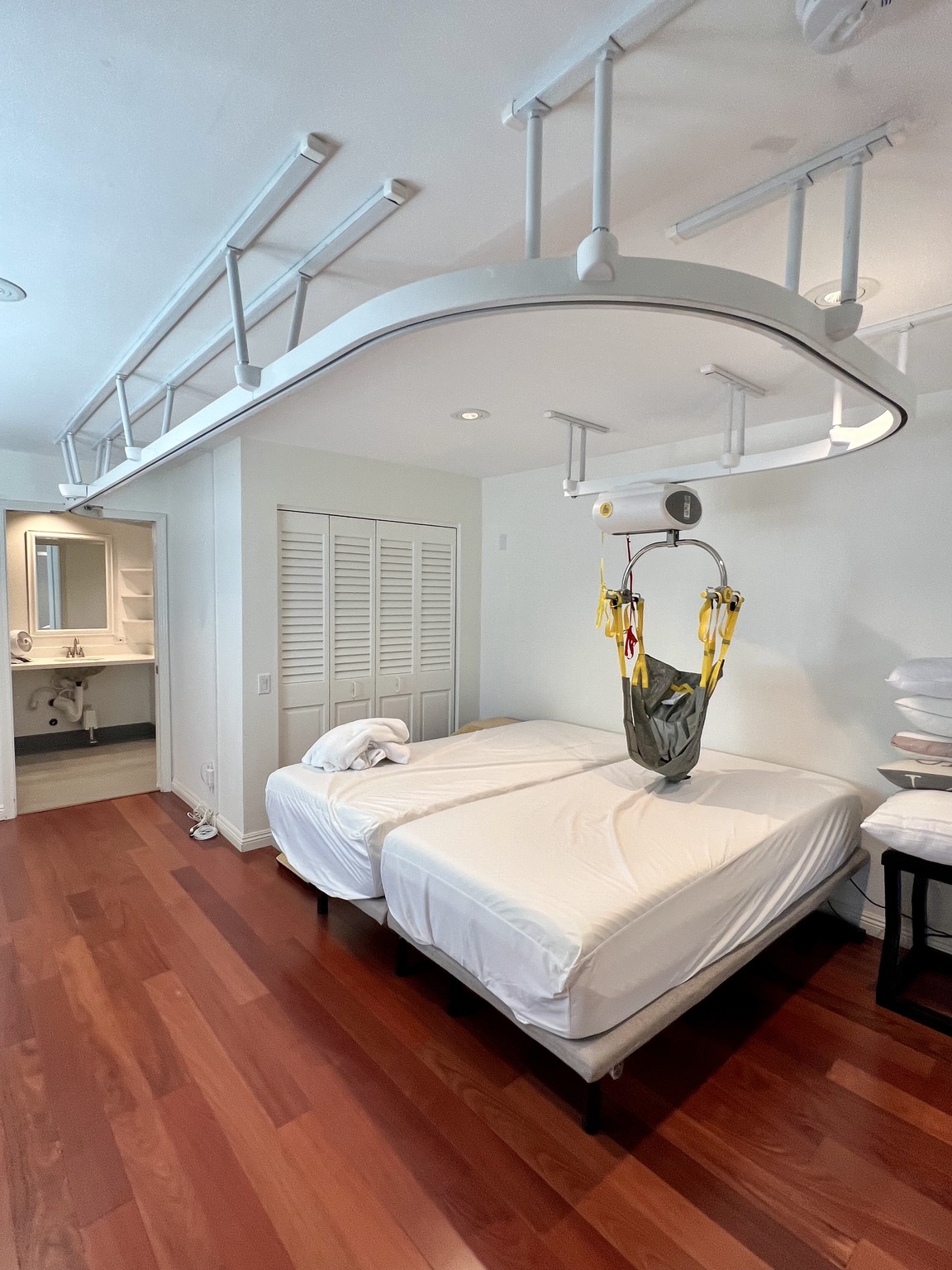 After ceiling-lift installation: overhead tracks and a lift above the bed in the same bedroom