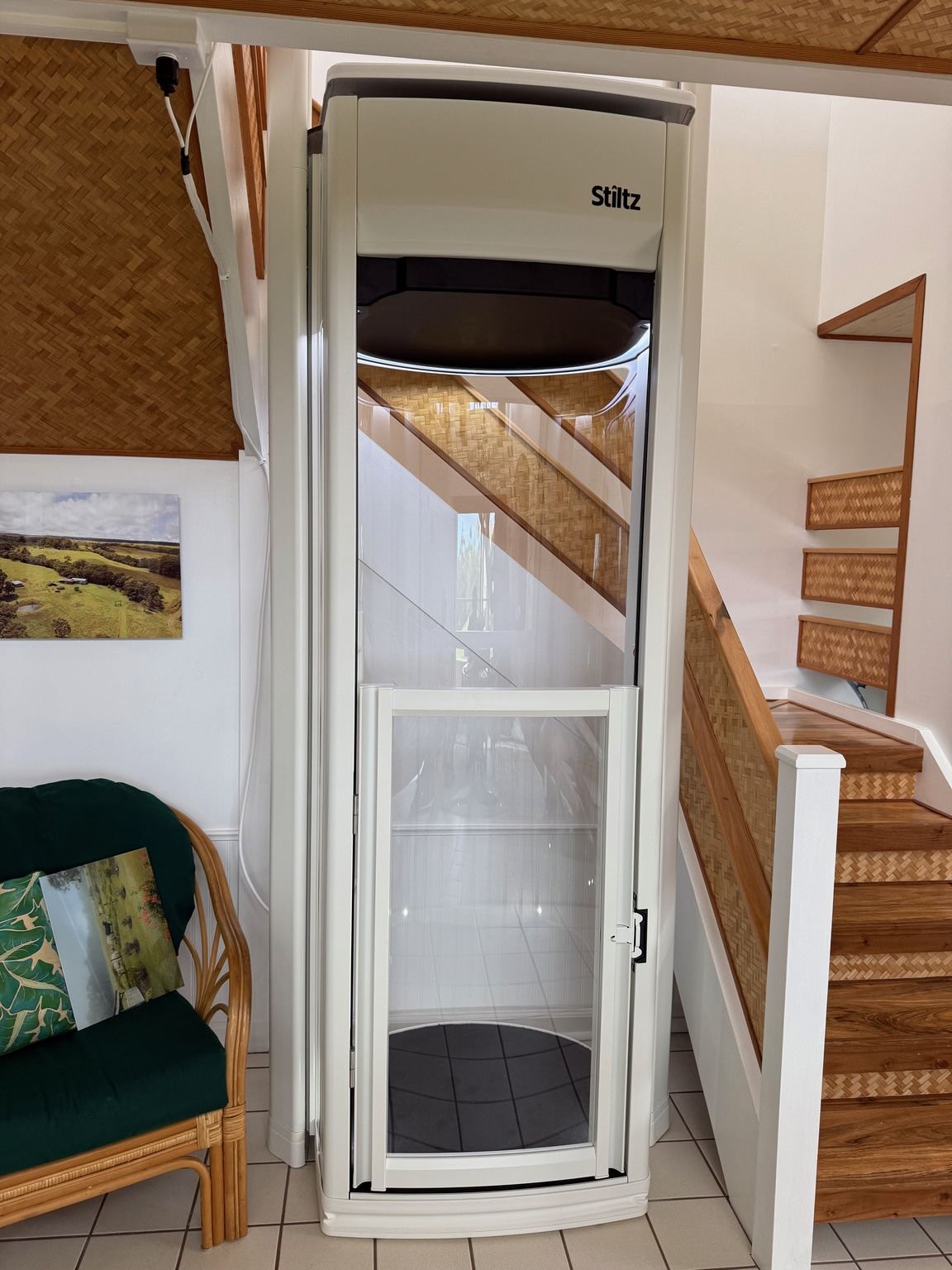 After Stiltz installation: the home lift in the same tiled space beside the woven-panel staircase